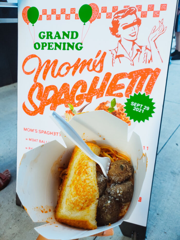 Photo of spaghetti with meatballs and half a slice of garlic bread in front of the Mom's Spaghetti sign (Eminem's new restaurant in Detroit).