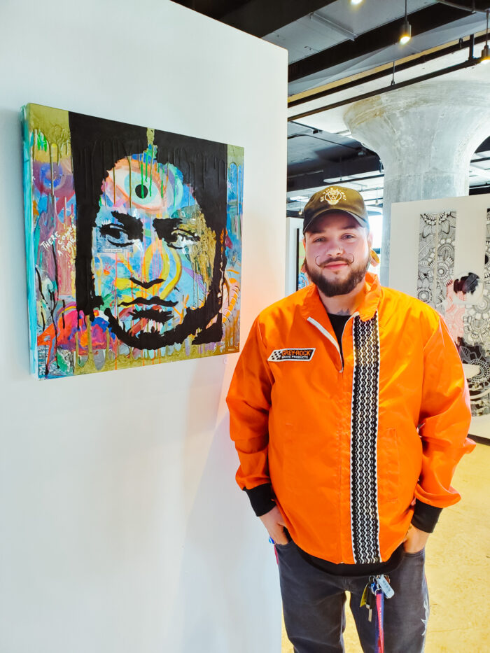 Photo of artist Blight Hernandez with his artwork "Evolution of Time" at the YOU Belong art exhibition in Detroit.